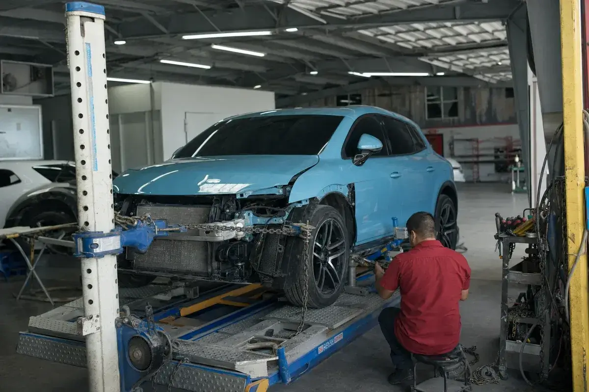A car clamped on a frame-straightening bench with pulling arms at Podium Body Works in Round Rock, Texas