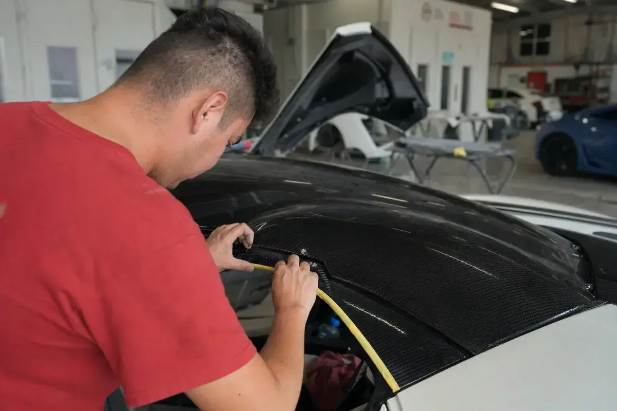 Finishing work on a carbon-fiber panel of an exotic car at Podium Body Works in Liberty Hill, Texas