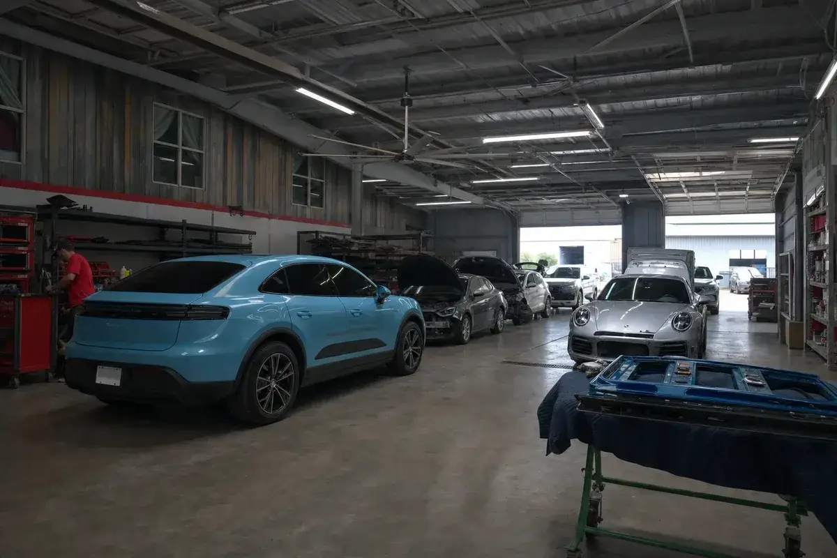 A wide view of the collision repair shop floor with cars in bays at Podium Body Works in Round Rock, Texas