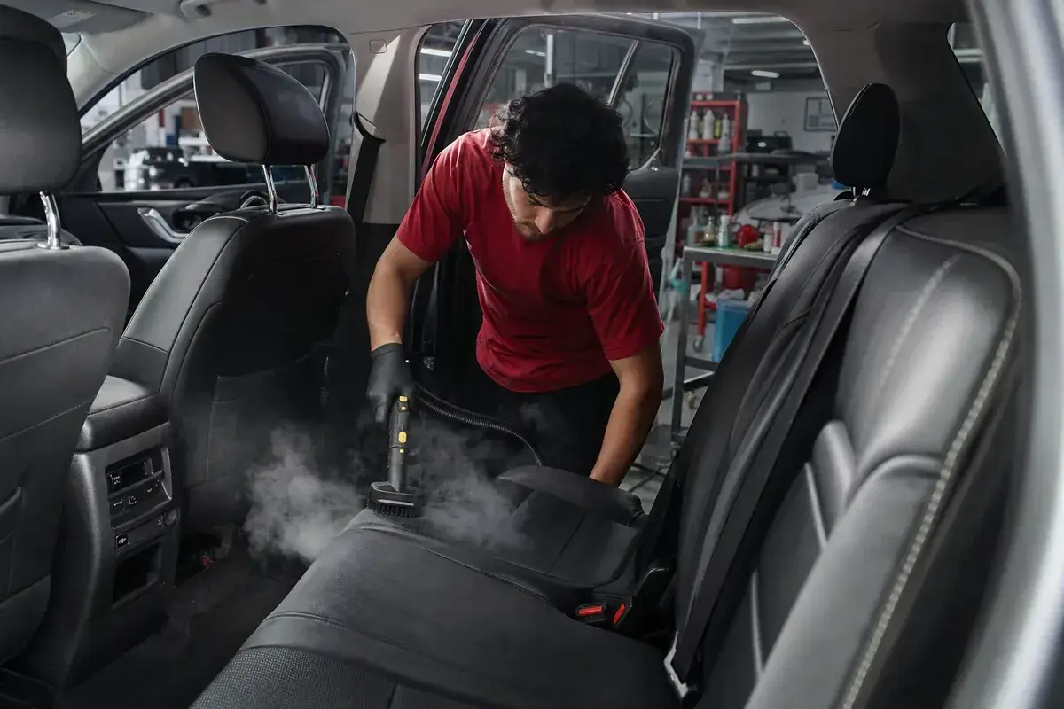 A detailer deep-cleaning the interior of an SUV at Podium Body Works in Round Rock, Texas