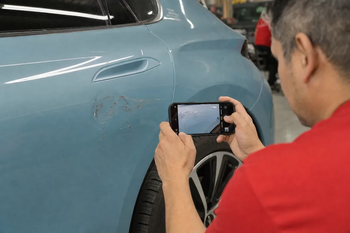 Documenting damage on a vehicle panel for an estimate at Podium Body Works in Round Rock, Texas