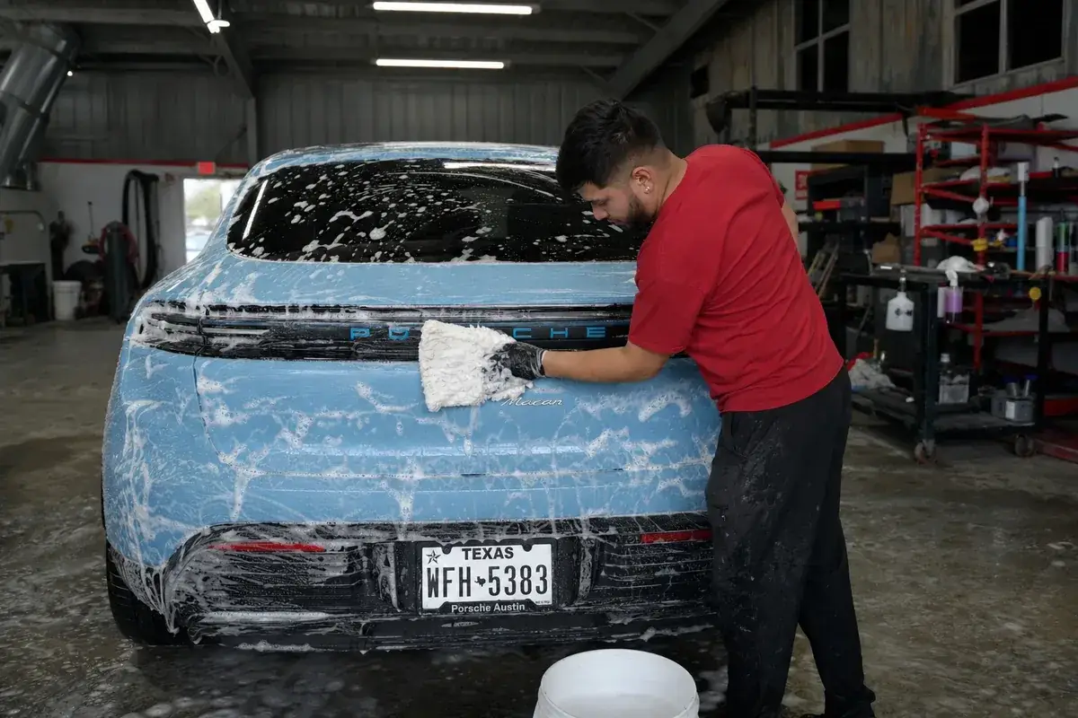 A technician performing an exterior decontamination wash at Podium Body Works in Round Rock, Texas