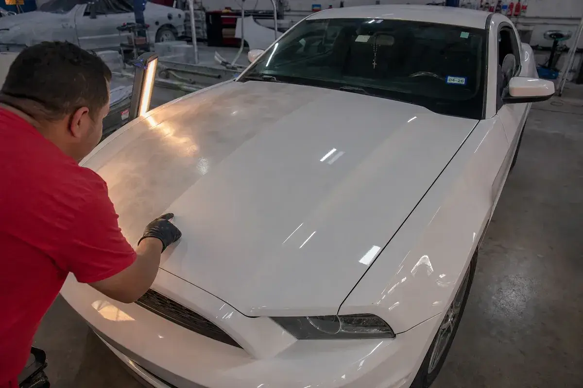 A hood shown before and after paint correction at Podium Body Works in Round Rock, Texas