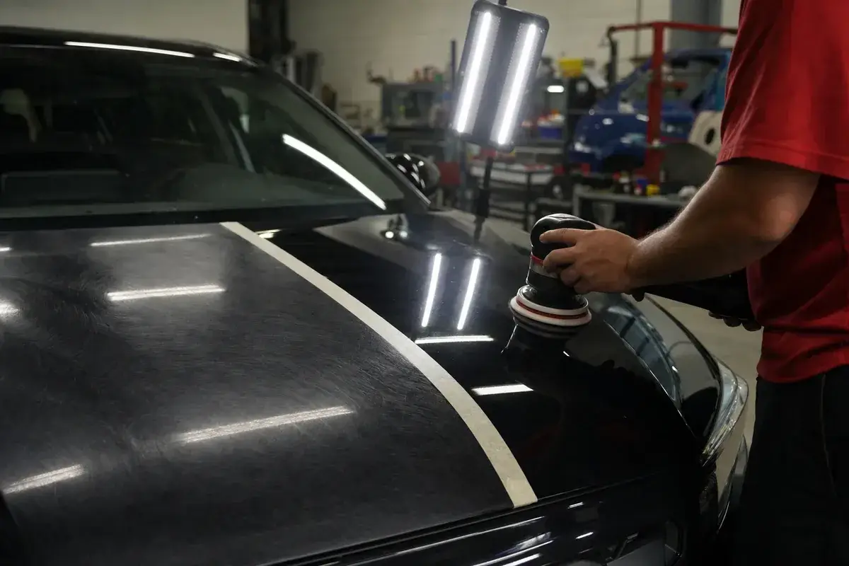 A hood shown half corrected and half swirled under inspection light at Podium Body Works in Round Rock, Texas